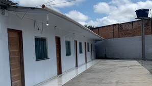 Un edificio con varios cuartos, un patio de concreto y un depósito de agua en el techo.