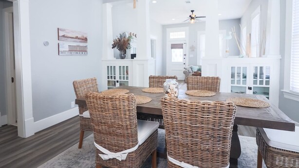 A dining area with wicker chairs, a wooden table, and a chandelier. - Vibrant Bungalow 2 Minutes to the Beach (Galveston)