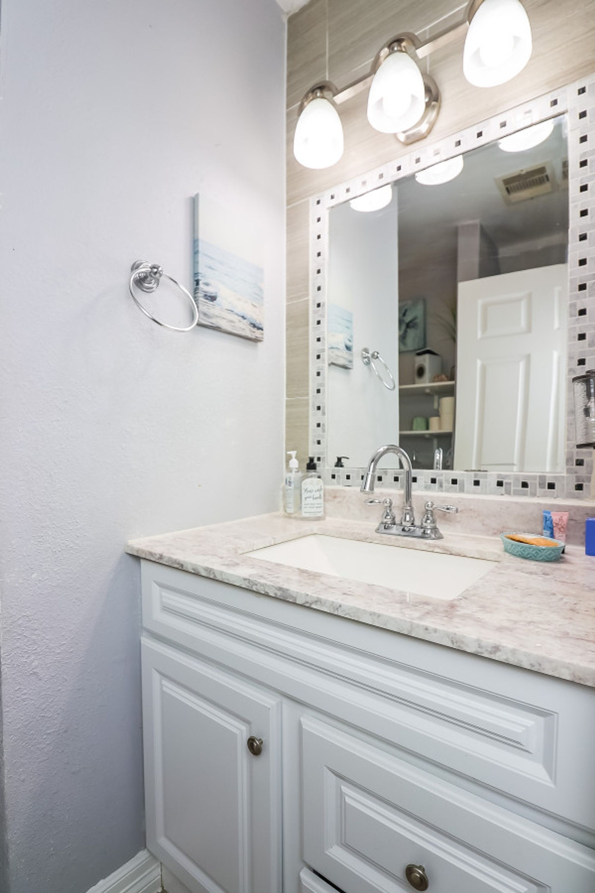 A bathroom with a white vanity, a sink, and a mirror with lights.