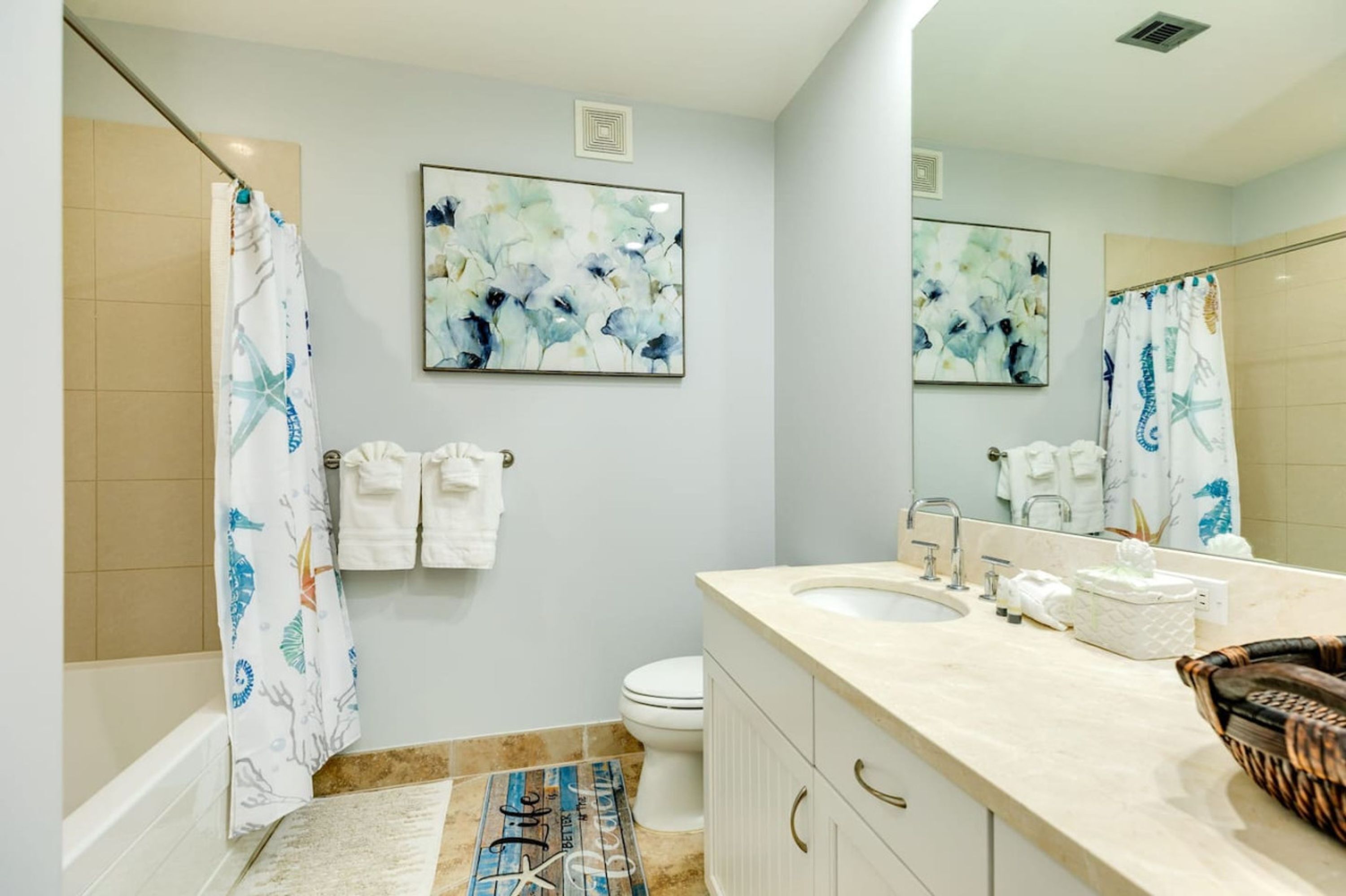 Une salle de bain avec une baignoire, une douche, des toilettes et un lavabo. Des serviettes sont accrochées au mur et un miroir se trouve au-dessus du lavabo.