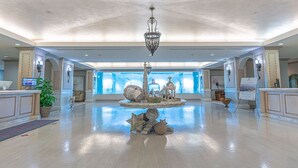 A spacious lobby with a central fountain, a chandelier, and a reception desk. - Warm and Welcoming Views at Diamond Beach (Galveston)