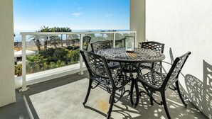 A balcony with a round table and four chairs, overlooking a beach and greenery. - Warm and Welcoming Views at Diamond Beach (Galveston)