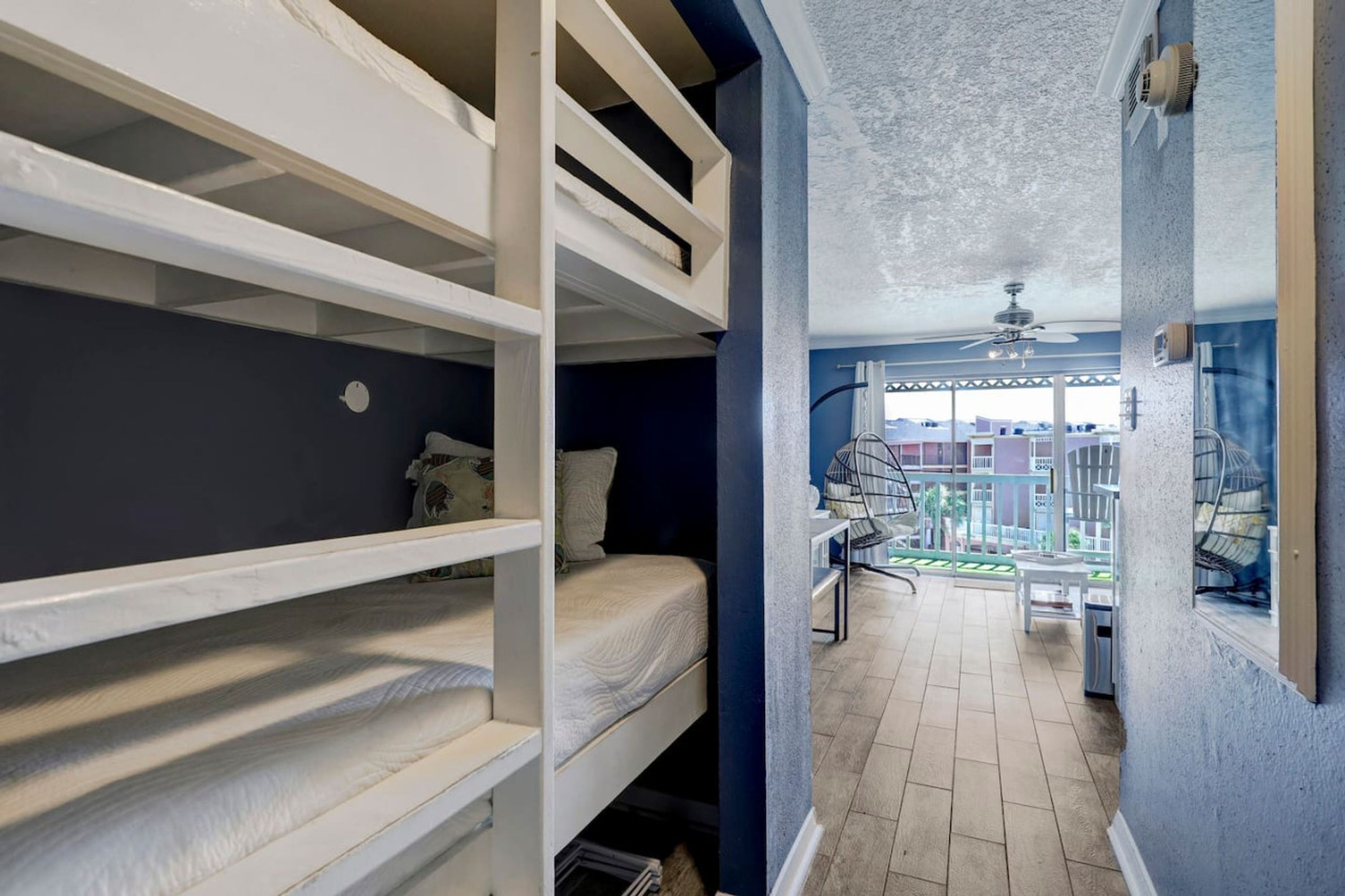 Una camera del dormitorio con letti a castello, un balcone con mobili da esterno e vista sulla città.