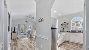 A modern kitchen with white cabinets, a stainless steel refrigerator, and a window overlooking the backyard. - Wild Iris Condo - Cozy Myrtle Beach Retreat (Myrtle Beach)