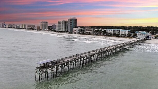 A long pier extending into the water with buildings in the background. - Wild Iris Condo - Cozy Myrtle Beach Retreat (Myrtle Beach)