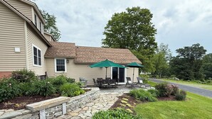 A house with a stone patio, outdoor furniture, and a garden. - Antique farmhouse with spectacular mountain view in a bucolic setting. (West Windsor)