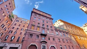 Un immeuble à plusieurs étages, doté d’une entrée centrale imposante et de nombreuses fenêtres.