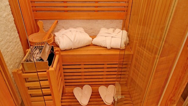 Un sauna en bois avec un banc, un récipient en bois et deux serviettes.