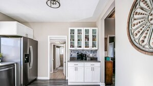 A modern kitchen with white cabinets, a stainless steel refrigerator, and a backsplash with small tiles. - Bristol Abode (Bristol)