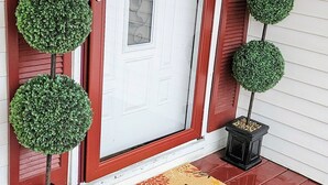A front door with a wreath, two potted topiary trees, and a welcome mat. - Bristol Abode (Bristol)