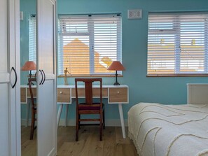 A bedroom with a bed, a desk, a chair, and two windows with blinds. - NEW Cosy 2 Bedroom Home | Free Parking + Garden (Canterbury)