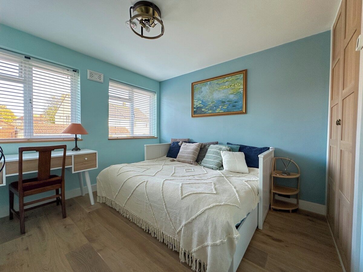 A bedroom with a bed, a desk, and a chair.