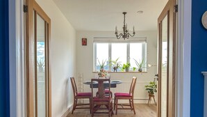 Un coin repas avec une table ronde et quatre chaises, un lustre et des plantes en pot.