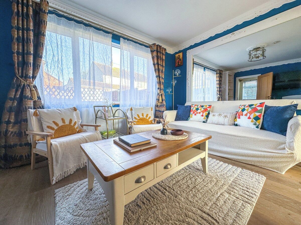 A cozy living room with a sofa, armchairs, a coffee table, and a bookshelf.