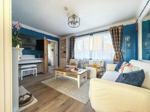 A living room with a sofa, coffee table, and a dining area with a piano. - NEW Cosy 2 Bedroom Home | Free Parking + Garden (Canterbury)