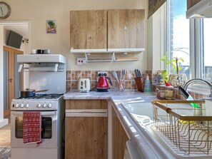 A kitchen with wooden cabinets, a gas stove, a toaster, and a sink. - NEW Cosy 2 Bedroom Home | Free Parking + Garden (Canterbury)