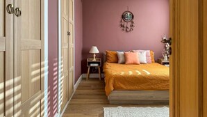 Une chambre à coucher avec un lit, une table de chevet, une lampe et un élément décoratif mural.
