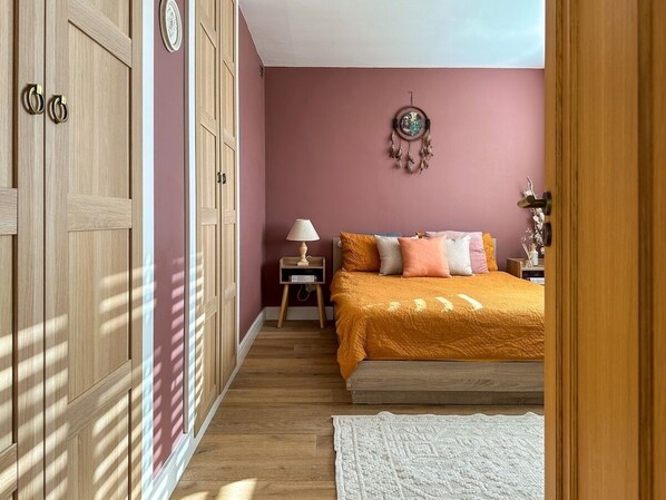 A bedroom with a bed, a nightstand, a lamp, and a wall decoration.