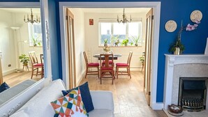 Un salon avec un canapé blanc, un coin repas avec une table ronde et des chaises, et une cheminée.
