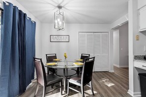 A dining area with a round table, black chairs, and a chandelier. There is a framed sign on the wall and a white closet in the background. - Charming Private Oasis - close to airport, mall, and downtown. (Raleigh)