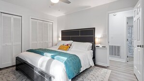 Ein Schlafzimmer mit Bett, Deckenventilator, Nachttisch und Kleiderschrank.