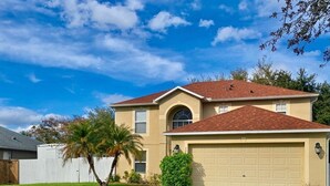 Una casa a due piani con un garage, un prato curato e un cielo sereno.