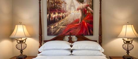 A hotel room with a large bed, two bedside tables with lamps, and a painting of a cityscape.