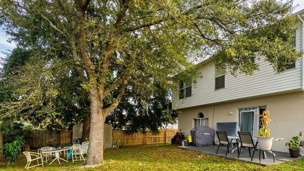 A backyard with a tree, a barbecue grill, and outdoor furniture. - 4-bedroom in at the Top Notch Villa in  Deltona, 25 min to Disney and Universal. (Deltona)