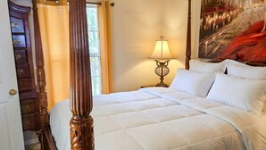 Una camera da letto con un letto a baldacchino, un comodino con una lampada, un quadro che raffigura una veduta cittadina e una finestra con tende.
