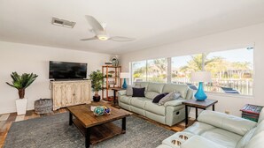 A living room with a sofa, coffee table, TV, and a ceiling fan. - Waterfront home (Marco Island)