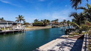A marina with boats docked, a waterway, and palm trees. - Waterfront home (Marco Island)