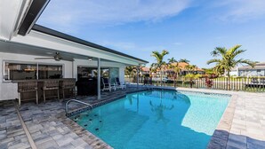 A swimming pool with a patio area, bar, and lounge chairs. - Waterfront home (Marco Island)