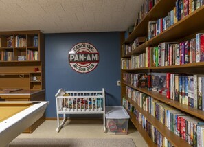 A library with bookshelves, a baby crib, and a wall sign.