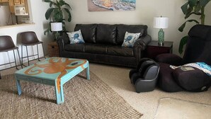 A living room with a sofa, coffee table, and chairs. There is a painting on the wall and a plant on the floor. - Near Manatees, Springs, Scalloping, & Black Diamond (Lecanto)