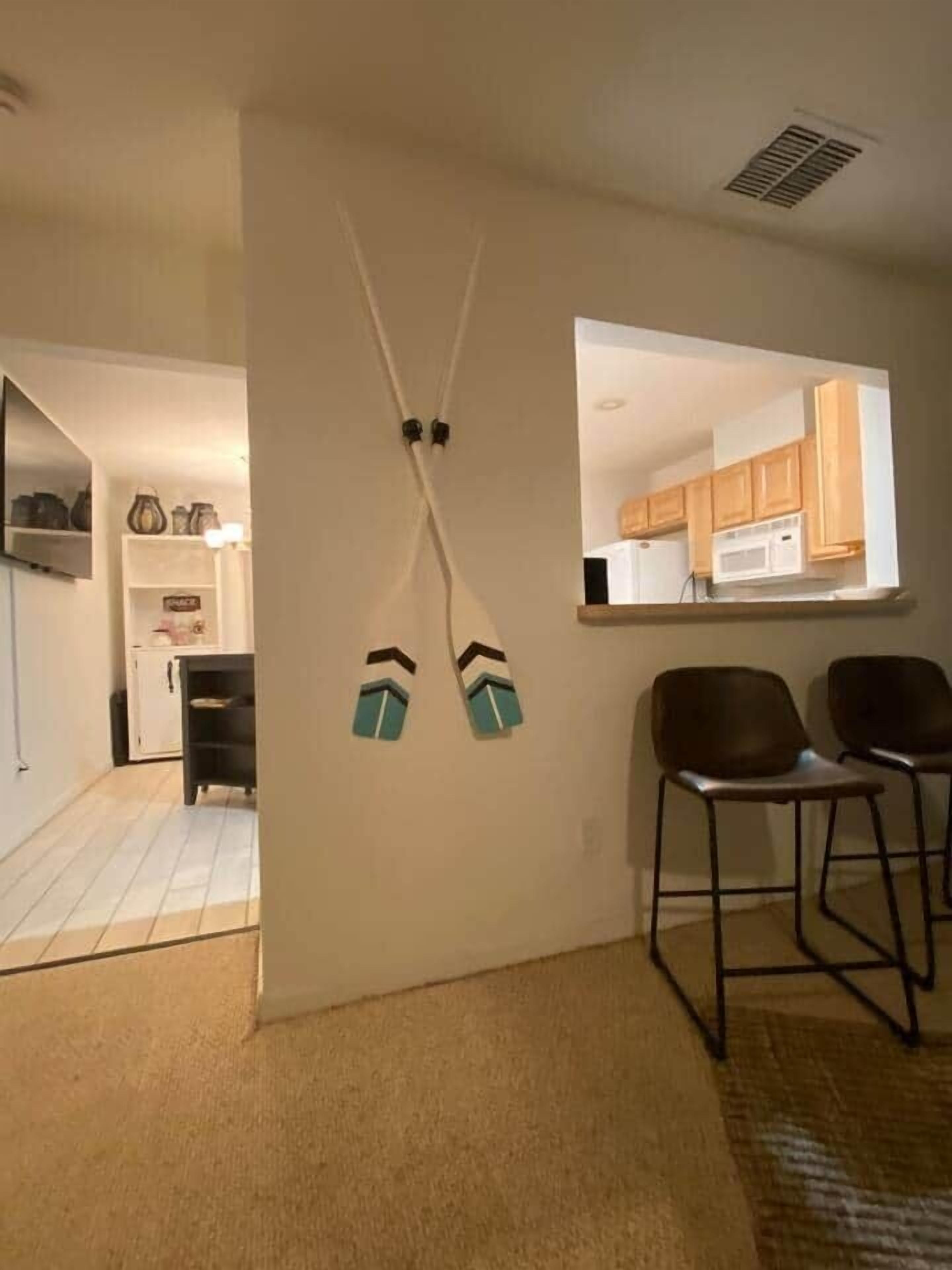 Een kamer met een kitchenette, een spiegel en twee stoelen.