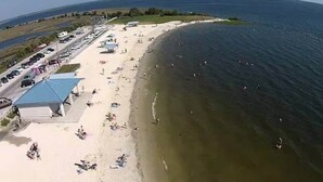 A beach with a parking lot, beach umbrellas, and a few people. - Near Manatees, Springs, Scalloping, & Black Diamond (Lecanto)