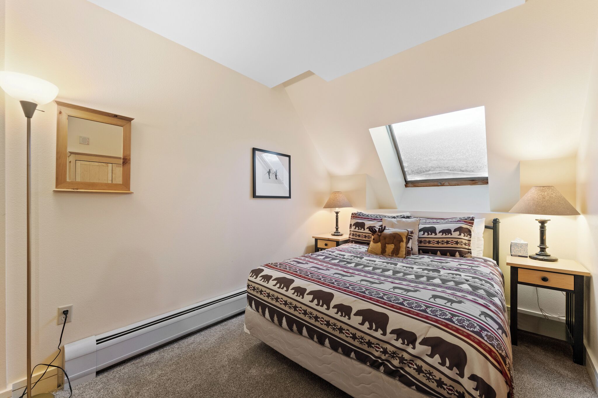 A bedroom with a bed, two bedside tables, a nightstand, a wall-mounted picture, and a window.