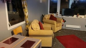 Een moderne woonkamer met een bank, een eettafel en een groot raam.