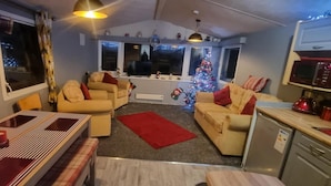 Een gezellige woonkamer met een zithoek, een eettafel en een kleine keukenhoek.