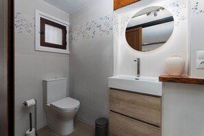 Un baño moderno con inodoro, lavamanos y espejo.