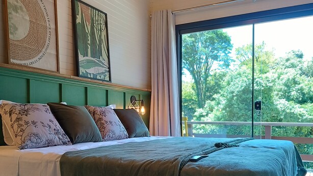 Un dormitorio con una cama grande, un cabecero verde y dos cuadros en la pared.
