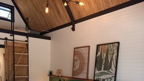 Un dormitorio con cama, techo de madera, decoración en la pared y una escalera.