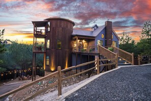 A rustic cabin with a wooden exterior, a balcony, and a staircase leading to the main entrance. - Unique Luxury Cabin with swimming pool, outdoor sauna, fire pit, and amazing tree top views! (Broken Bow)