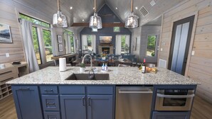 A kitchen with granite countertops, blue cabinets, a dishwasher, and an oven. - Unique Luxury Cabin with swimming pool, outdoor sauna, fire pit, and amazing tree top views! (Broken Bow)
