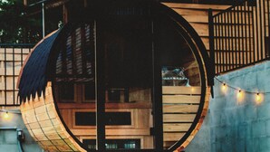 A building with a circular wooden structure, a staircase, and string lights. - Unique Luxury Cabin with swimming pool, outdoor sauna, fire pit, and amazing tree top views! (Broken Bow)