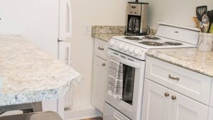 Una cocina compacta con estufa, microondas y cafetera sobre la encimera.