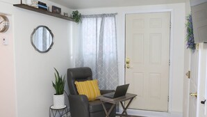Una sala de estar con un sillón de cuero oscuro, una mesita auxiliar, una computadora portátil, una planta en maceta y una estantería.