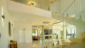 Un intérieur moderne avec un escalier en verre, un coin repas et une cuisine.