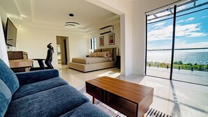 Un salon moderne avec un canapé, une table basse et une grande fenêtre donnant sur la mer.