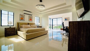 Une chambre spacieuse avec un grand lit, un téléviseur à écran plat et une vue sur l’extérieur.